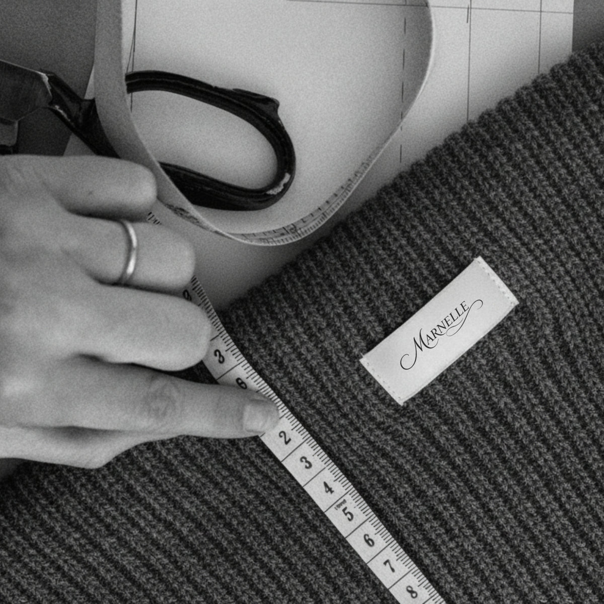 Person measuring a roll of fabric with a measuring tape on a textured surface, with a brand label visible.